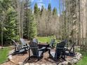 Inviting outdoor firepit area surrounded by mature trees and comfortable Adirondack chairs at 290 Broken Lance Dr # B104, Breckenridge, CO 80424