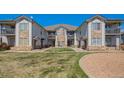 Well-maintained condo building with stone accents and lush green lawn under a clear blue sky at 3250 E 103Rd Pl # 805, Thornton, CO 80229