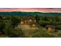 Exterior of home at sunset with a two-car garage and small outbuilding at 8403 Homestake Ct, Larkspur, CO 80118