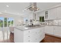 Modern kitchen island with a cooktop, white cabinets, and a view of the spacious living area at 2945 E 26Th Avenue Pkwy, Denver, CO 80205