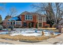 Brick two-story house with a landscaped yard and snow on the ground at 6150 S Fulton St, Englewood, CO 80111