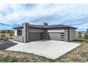 Side view of the three-car garage with sleek gray doors and a spacious concrete driveway at 2730 Fox View Trl, Franktown, CO 80116