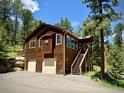 Two-story home with a two-car garage, wooden exterior and staircase leading up to the front door at 6752 S Columbine Rd, Evergreen, CO 80439