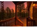 Wood porch with wooden railing offers views of the trees at dusk at 6752 S Columbine Rd, Evergreen, CO 80439