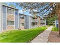Two-story condo with stone accents, a balcony, well-maintained lawn and blue sky backdrop at 8600 E Alameda Ave # 22-208, Denver, CO 80247