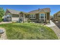 Lush backyard featuring a well-maintained lawn, stone pathway, and covered porch at 15347 Quince Cir, Thornton, CO 80602