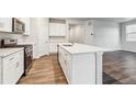Bright kitchen features an island, stainless appliances, and white cabinets at 1464 Orchard St, Brighton, CO 80601