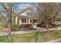 Inviting yellow home featuring a cozy front porch and mature trees at 8865 E 28Th Ave, Denver, CO 80238
