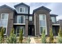 Modern townhome with gray brick and siding, a walkway to the front door, and young evergreens for curb appeal at 14673 E Belleview Dr, Aurora, CO 80015