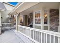 Inviting covered porch featuring a decorative door, stone accents, and outdoor seating at 24422 E Frost Dr, Aurora, CO 80016