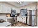 Efficient kitchen with stainless steel appliances, white cabinets, and wood-look flooring at 1920 S Hannibal St # B, Aurora, CO 80013
