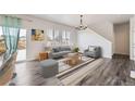 Bright living room featuring a gray sofa set, natural light, and stylish chandelier at 17189 E 103Rd Pl, Commerce City, CO 80022