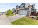 The gray two-story home features an attached two car garage, and a well-manicured lawn at 7018 E 123Rd Pl, Thornton, CO 80602