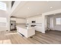 Modern white kitchen with large island, stainless steel appliances, and hardwood floors at 39836 Floyd St, Elizabeth, CO 80107