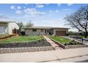 Charming single-story home featuring a well-manicured lawn and a stone pathway leading to the front door at 9508 Lou Dr, Northglenn, CO 80260