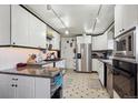 Well-lit kitchen featuring ample white cabinetry, granite countertops, modern appliances, and stylish tile flooring at 9508 Lou Dr, Northglenn, CO 80260