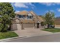 Charming two-story home featuring a three-car garage, stone accents, and a well-manicured lawn at 22665 E Calhoun Pl, Aurora, CO 80016