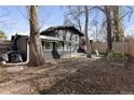 Backyard with trees and play structure behind a black home with a fenced in backyard at 1345 S Ivy Way, Denver, CO 80224