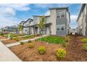 View of the exteriors of multiple gray townhomes with sidewalks and grass lawns at 20530 E 58Th Ave, Aurora, CO 80019