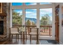 Cozy living area with a stone fireplace and picturesque mountain views through large windows at 28364 Tresine Dr, Evergreen, CO 80439