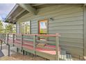 Home's charming entryway with a red deck leading to a glass-paneled door at 29304 Thimbleberry Ln, Evergreen, CO 80439