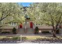 Charming townhouse exterior featuring a red door, steps, and lush flowering trees in a well-maintained neighborhood at 880 E 16Th Ave # D, Denver, CO 80218