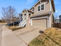 Two-story home showcasing an attached garage, with a red door and stone siding accents at 3155 Kedleston Ave, Highlands Ranch, CO 80126