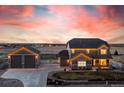 A beautiful two-story home with a separate garage is illuminated against a stunning twilight sky at 11343 E 163Rd Ct, Brighton, CO 80602