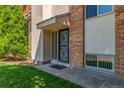 A ground level apartment featuring a secure entry door, brick accent wall, and an inviting outdoor setting at 6455 E Bates Ave # 4-105, Denver, CO 80222