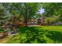 Apartment building exterior featuring a well-manicured lawn and mature trees providing shade and a bench for relaxation at 6455 E Bates Ave # 4-105, Denver, CO 80222
