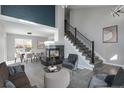 Open concept living room with fireplace, staged furniture, and gray flooring at 4575 Gibraltar St, Denver, CO 80249