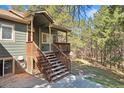 A welcoming wood front porch with steps leads to the entrance of the home, surrounded by trees at 34103 Forest Park Dr, Elizabeth, CO 80107
