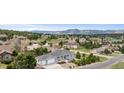 A scenic aerial view of a residential area with well-maintained homes, lush trees, and mountain views on a sunny day at 1553 Plowman Dr, Monument, CO 80132
