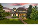 Charming two-story home with a manicured lawn and inviting stone pathway, beneath a beautiful sunset at 12665 S Robinson Ranch Ct, Parker, CO 80134