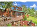 Wooden deck with a seating area and grill that overlooks a backyard surrounded by trees at 30122 Nancys Ln, Conifer, CO 80433