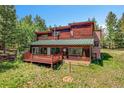 Back exterior of a wooden home with green roof and a wooden deck surrounded by lush greenery at 30122 Nancys Ln, Conifer, CO 80433