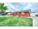 A well-maintained, single-story red brick home with a green lawn and concrete driveway at 9100 Yucca Way, Thornton, CO 80229