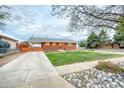 A charming brick home with a green lawn, concrete driveway, and covered parking at 9100 Yucca Way, Thornton, CO 80229