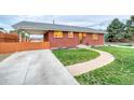 A well-maintained, single-story red brick home with a green lawn and concrete driveway at 9100 Yucca Way, Thornton, CO 80229