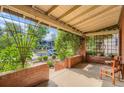 Inviting covered porch with brick detailing, climbing vines, and outdoor seating with neighborhood view at 827 S Sherman St, Denver, CO 80209