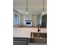 Open kitchen with a stylish sink, modern pendant lights, and fireplace with a white brick surround at 901 Coal Bank Trl, Castle Rock, CO 80104