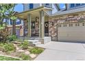 Inviting covered front porch with stone pillars and a well-manicured garden and stone walkway at 2312 Dogwood Dr, Erie, CO 80516