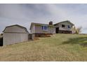 Lawn view showcasing the house's multiple levels and the brick and stone elements of the foundation at 11810 Mesa View Rd, Larkspur, CO 80118