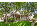 Charming home with stone accents, a covered front porch, manicured lawn, and mature trees at 14246 Piney River Rd, Broomfield, CO 80023