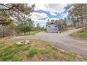 Long driveway leading to a two-car garage with lush surroundings and green space at 721 Forest View Rd, Monument, CO 80132