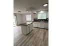 Updated kitchen featuring an island, white cabinets, and wood-look flooring with a sliding door to the backyard at 14598 E Evans Ave, Aurora, CO 80014
