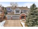 Inviting two-story home with a brick-accented entryway and a three-car garage at 7065 Campden Pl, Castle Pines, CO 80108