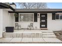 Inviting front porch with chairs, a black front door, and a white brick facade at 1045 W 101St Ave, Northglenn, CO 80260