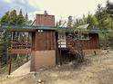 A charming cabin with wood siding, large deck, concrete pad, and set amongst the trees at 542 Harris Dr, Idaho Springs, CO 80452