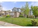 Beautifully landscaped front yard with mature trees and shrubs surrounding this charming two-story brick home at 907 Eldorado Dr, Superior, CO 80027